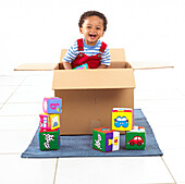 Boy standing inside a cardboard box holding a cube