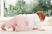Baby girl crawling on mat on all fours