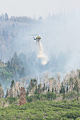 Firefighter helicopter dropping water on wildfire,