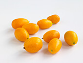 Eight small yellow kumquats, one cut in half