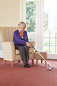 Older woman sitting in a chair using a pick up stick