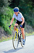 Woman riding racing bike on road in Italian countryside