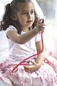 Girl sitting on bed holding up stethoscope