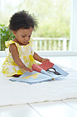 Baby girl sitting playing with fabric picture book