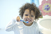 Girl holding toothbrush to mouth