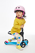 Little girl in yellow playing with scooter
