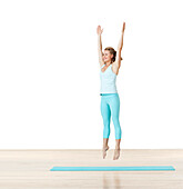 Woman practising standing jump Pilates mat exercise