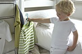 Boy in bedroom holding stripy jumper on clothes hanger