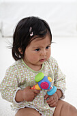 Baby girl sitting on carpet holding rattle toy