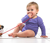 Baby girl chewing string of pull along toy