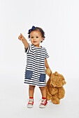 Little girl in stripey dress playing with bear