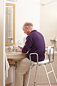 Man sitting on a raised seat in front of bathroom basin