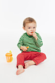 Little boy in green stripey top eating a carrot stick