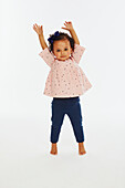 Little girl in pink top playing with arms up in the air
