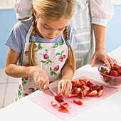 Girl slicing strawberries on chopping board