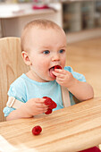 Baby girl feeding herself raspberries
