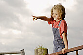 Girl standing on fence pointing