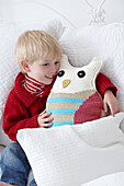 Boy hugging a crocheted owl cushion