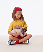 Girl holding a lop-eared rabbit in her lap