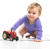 Baby girl crawling with toy tractor
