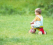 Boy riding a four wheeled wooden bike on grass