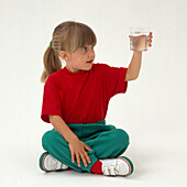 Child sitting cross-legged with glass of water