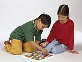 Boy and girl sitting playing snakes and ladders