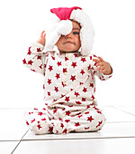 Baby girl sitting wearing a Christmas hat
