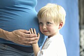 Boy leaning his head against pregnant woman's belly