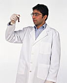Doctor in laboratory coat holding up a phial of blood