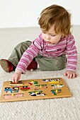 Baby girl wearing stripy top playing with wooden puzzle