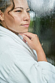 Woman in bathrobe at rainy window
