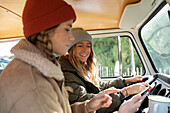 Young women friends using smartphone in van