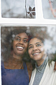 Happy mother and daughter looking out window