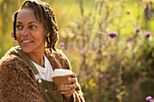 Smiling woman enjoying coffee in sunny garden