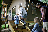 Family holding hands walking up steps to cabin