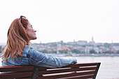 Woman with eyes closed sitting on a bench
