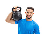 Happy young man holding kettlebell on shoulder