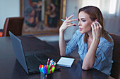 Woman on a laptop using wireless earphones