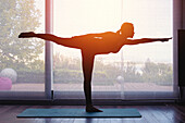Silhouette of woman doing yoga at home at sunset