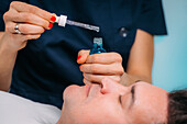 Cosmetician applying hyaluronic acid serum to man's face