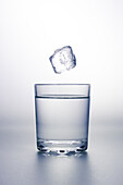 Ice cube falling into glass of water, illustration