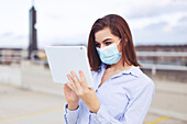Young businesswoman in facemask using digital tablet