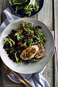 Grilled chicken breast served with a mix of green lettuce, black lentils and olives