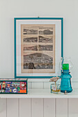 Old landscape photos in blue frame above shelf with decoration