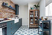 Bright kitchen with kitchen cabinets, exposed brickwork, and patterned tiles
