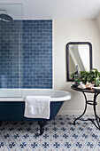 Freestanding bath and round table in a bathroom with patterned floor tiles