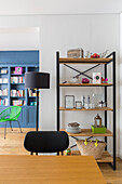 View over dining table to open shelving unit with decorative objects