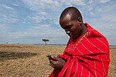Masai man typing a message into a mobile device