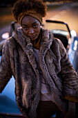 Confident young woman in fur coat at convertible